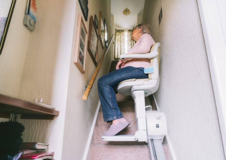 A Royal Fuji wheelchair lift in use, securely transporting a person in a wheelchair between floors in a residential setting.