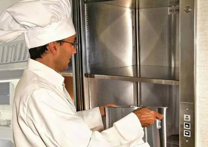 Chef arranging food vessel in dumbwaiter elevator
