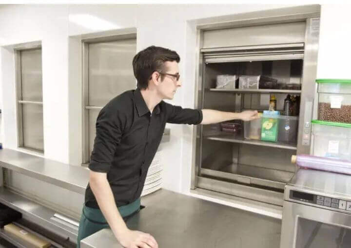 Man arranging food in a dumbwaiter
